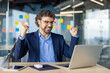 © Liubomir - Mature experienced businessman in business suit is looking at successful achievement results, boss with laptop inside office holding hands up, gesture of success, triumph, online notification laptop.