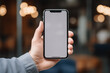 © Catbjorhan - Close up of a hand holding a smartphone with white screen, mockup, blurred background, generative ai