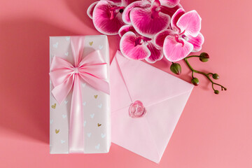 Wall Mural - One gift box with an envelope and orchid branches on a pink background.