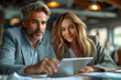 © missty - Male and female colleagues looking at tablet PC. Business people are working at desk. Image of two colleagues discussing about new project. Successful business couple talking and using digital tablet