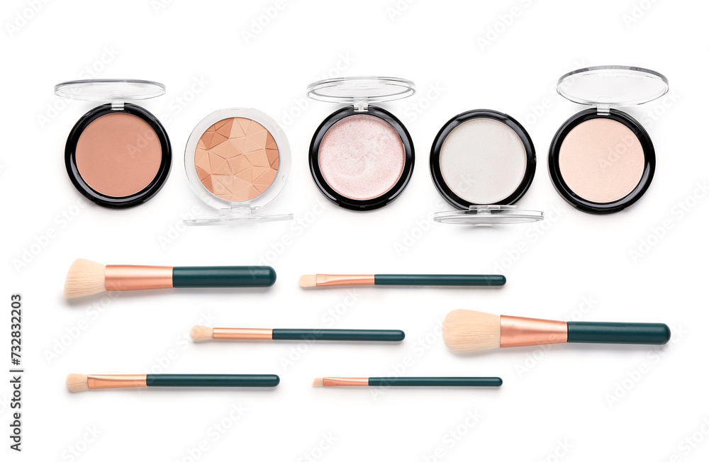 Makeup brushes and highlighters on white background