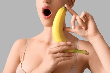 Poster - Young woman with banana on light background, closeup. Sex concept