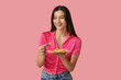 Beautiful young woman with french fries on pink background
