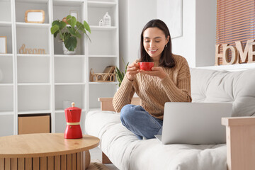 Poster - Pretty young woman enjoying coffee break at home with laptop on sofa