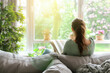 © aguadeluna - Young woman reading book while sitting on sofa at home, back view. Wellness at home concept.