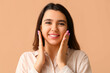 © Pixel-Shot - Young happy smiling woman with hands near face on beige background