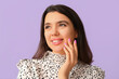 © Pixel-Shot - Young happy smiling woman with hand near face on lilac background, closeup