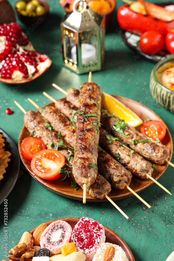 Traditional Eastern dishes and Muslim lantern on green table. Ramadan celebration