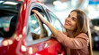 © PETR BABKIN - A happy woman inspects a car at a car dealership before purchasing.