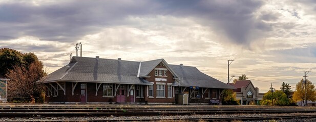 Canvas Print - Picturesque railway station illuminated by the warm, orange light of the setting sun