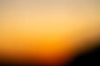 Abstract defocused shot of the sky during sunset hours casting a deep orange light