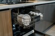 © Koplexs-Stock - Dishwasher with lots of plates and silverware inside, seen from the side