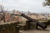 Fototapeta Tęcza - Old cannons in the Lisbon bastion. Castelo de S. Jorge cannons and view on the city. Ancient weapons.