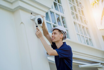 Wall Mural - A technician installs a CCTV camera on the facade of a residential building.