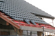 Installation of graphite roof tiles on wooden beams, a breather and waterproofing membrane, grey sky in the background