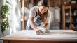 © Ameer - Happy smiling woman sanding old wooden table with sponge for furniture renovation and home improvement project
