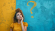 © pegasus24.com - Eine junge Frau steht vor einer gelb und blauen Wand sie überlegt oder denkt nach und sieht ein Fragezeichen an der Wand
