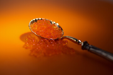 Wall Mural - Red Caviar in a spoon. Caviar over orange background. Fish roe, Close-up salmon or trout caviar. Delicatessen. Gourmet food. Texture of caviar. Seafood 