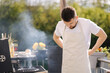 © Aleksandr - Man puts on an apron outdoor. Preparing for BBQ grill