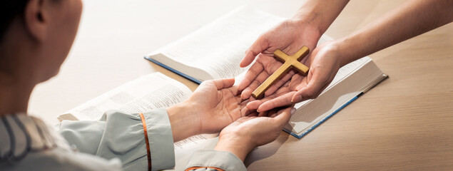 Close-up women prayer deliver holy bible book and holy cross to young believer. Spreading religion symbol. Concept of hope, religion, christianity and god blessing. Warm background. Burgeoning.