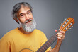 © luengo_ua - Aged man with a guitar on grey background
