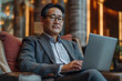 © Darya Lavinskaya - Asian Businessman sitting in the hotel lobby working with laptop. Business travel concept