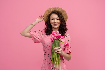 Wall Mural - pretty young woman posing isolated on pink studio background with tulips flowers