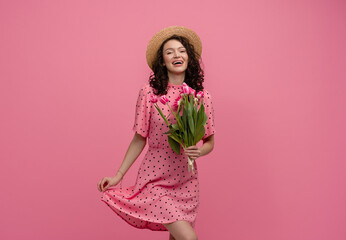 Wall Mural - pretty young woman posing isolated on pink studio background with tulips flowers