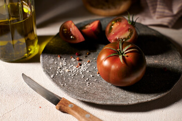 Wall Mural - Red-green tomatoes close up on a stone plate with olive oil