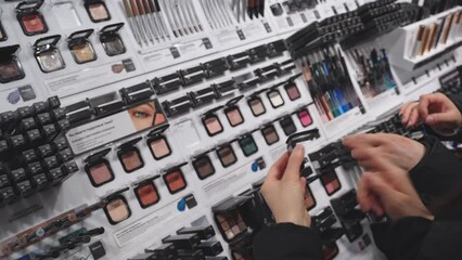 Poster - Decorative cosmetics samples and testers. Store interior, make up shelf. Unrecognizable female customers choosing products, choose color tone of powder shadows. Minsk, Belarus - february 10, 2024