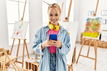 Wall Mural - Young caucasian woman artist using smartphone standing at art studio