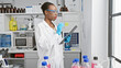 Passionate african american female scientist in lab gloves, fascinated by the power of medical research, deeply engrossed in taking notes at an indoor science laboratory