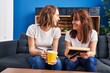 © Krakenimages.com - Two women mother and daughter drinking coffee looking photo at home