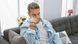 © Krakenimages.com - Thoughtful man contemplating while sitting on a gray sofa in a modern living room interior