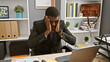 © Krakenimages.com - Stressed african man in a suit feeling headache at his office desk, showing work fatigue in a corporate environment.