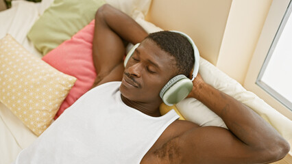 A relaxed african american man enjoying music with headphones in a comfortable home setting.