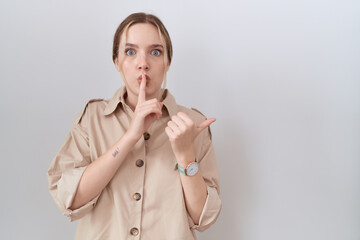 Poster - Young caucasian woman wearing casual shirt asking to be quiet with finger on lips pointing with hand to the side. silence and secret concept.