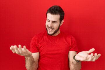 young hispanic man wearing casual red t shirt smiling showing both hands open palms, presenting and 