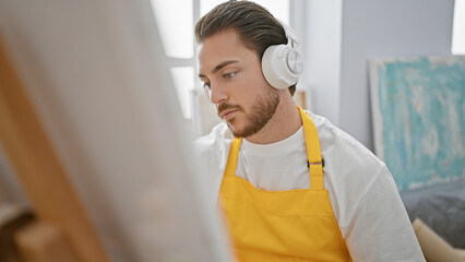 Wall Mural - Young hispanic man artist listening to music drawing at art studio