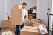 © Krakenimages.com - Young man smiling confident holding packages at new home
