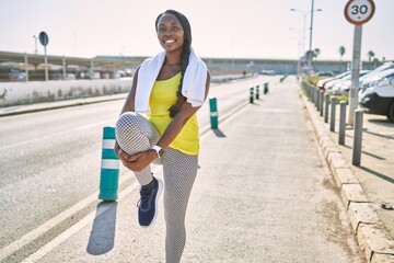 Sticker - African american woman wearing sportswear stretching leg at street