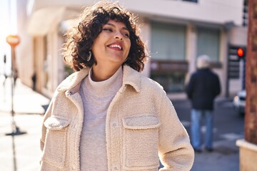 Wall Mural - Young beautiful hispanic woman smiling confident looking to the side at street