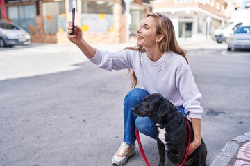 Poster - Young blonde woman make selfie by smartphone standing by dog at street