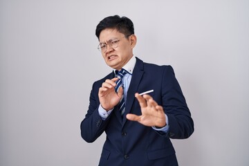 Sticker - Young asian man wearing business suit and tie disgusted expression, displeased and fearful doing disgust face because aversion reaction.