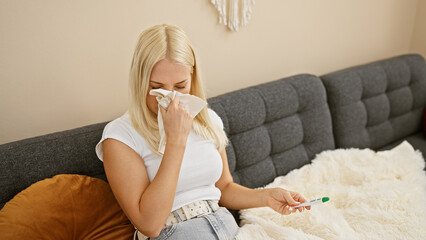 Sticker - Virus-stricken young blonde woman at home, beautiful yet unwell, desperately sneezing and measuring fever on sofa in the indoors, an illness portrait in the living room background