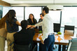 © AntonioDiaz - Diverse team of businesspeople putting their hands together in a meeting room