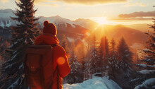 The Lonely Tourist In A Bright Orange Jacket Is Observing A Stunning Sunset Landscape In The Wild Pinewood Forest. High Snowy Mountains Are Visible In The Background.