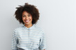 © pham - A woman with an afro hairstyle stands confidently in front of a plain white wall.