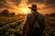 © imagemir - Farmer standing in the field of sunflower at sunset time.