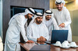 © oneinchpunch - Group of corporate arab businessmen meeting in the office - Business people wearing emirati clothing  working in the office